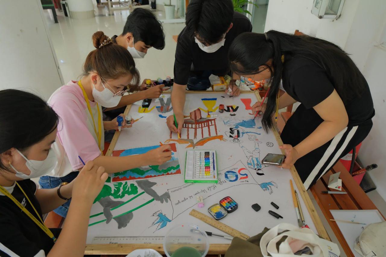 A group of people painting on a table Description automatically generated