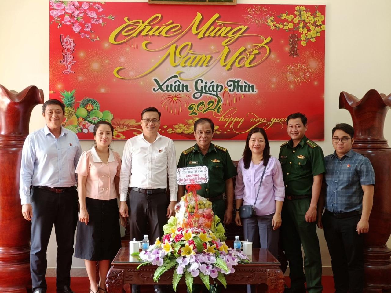 A group of people standing in front of a cake
Description automatically generated