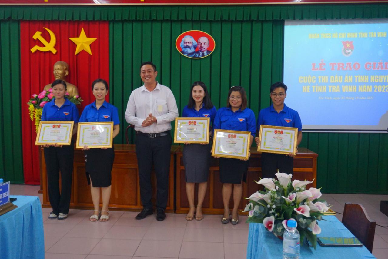 A group of people standing in front of a green curtain
Description automatically generated