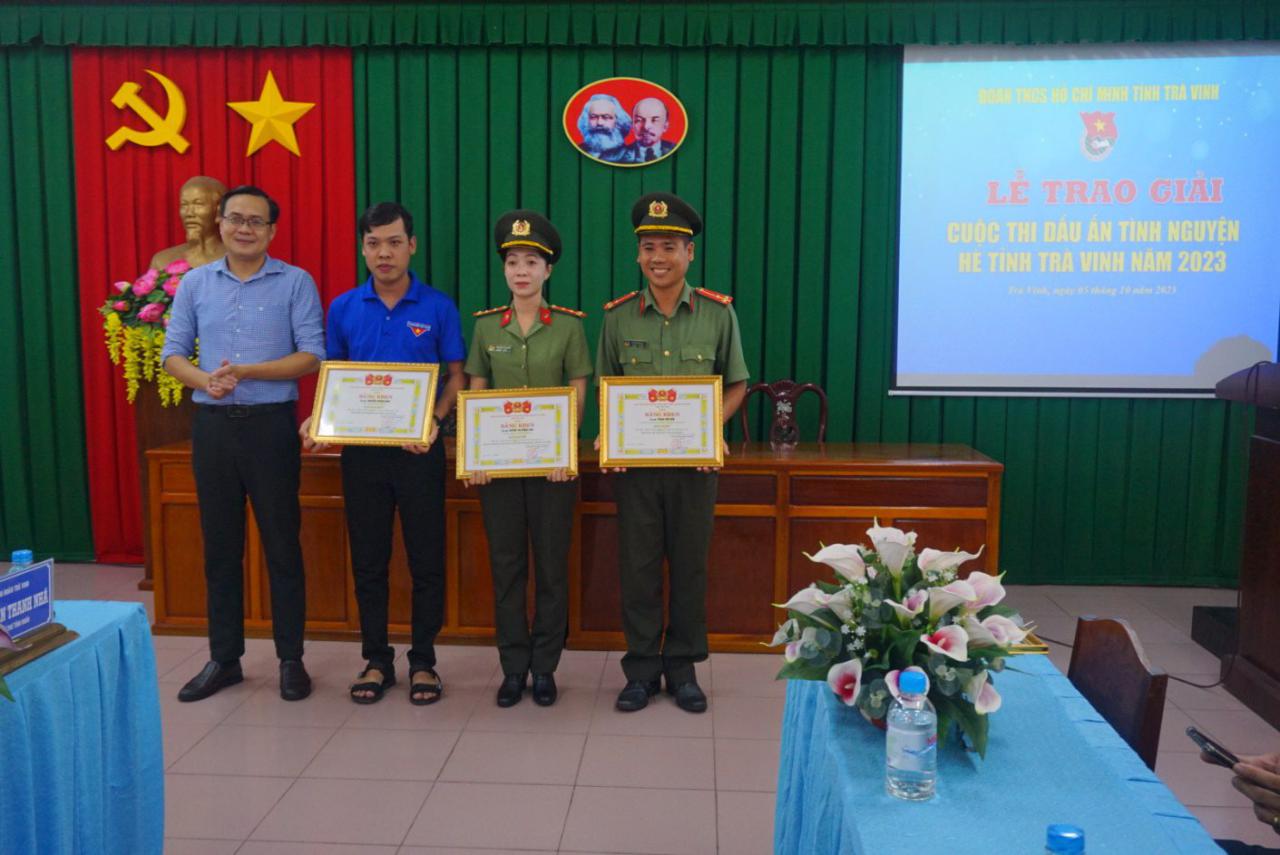 A group of people standing in front of a screen
Description automatically generated