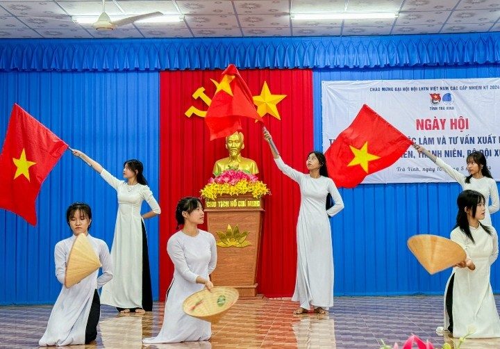 A group of women in white dresses holding flags Description automatically generated