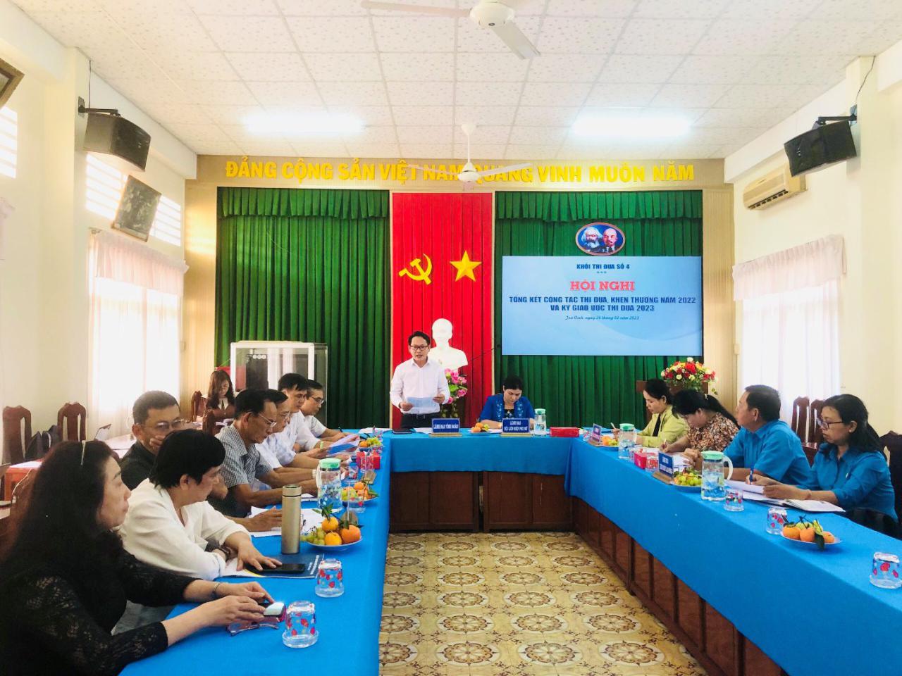 A group of people sitting at long blue tables in a room with green curtains
Description automatically generated with low confidence