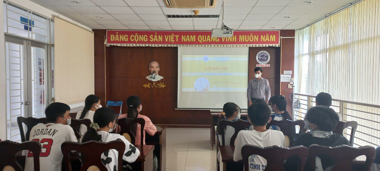 A group of people sitting in a room Description automatically generated with low confidence