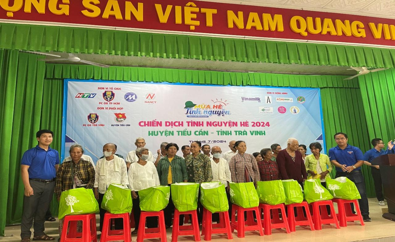 A group of people standing in front of a banner Description automatically generated