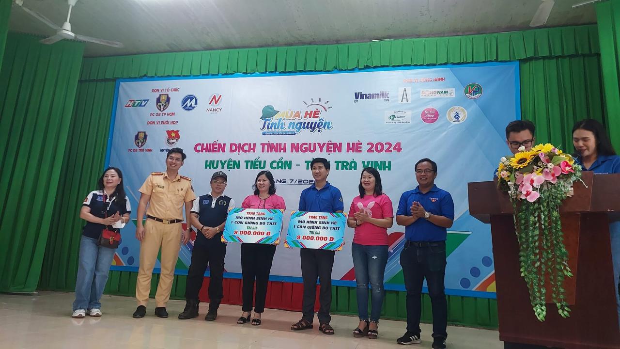 A group of people standing in front of a banner Description automatically generated