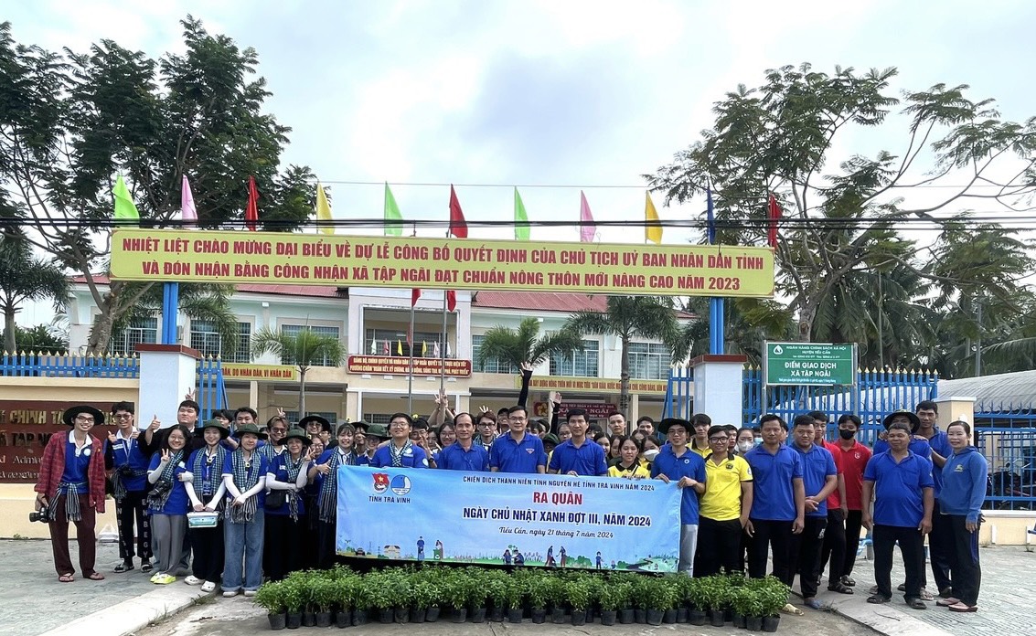 A group of people standing in front of a sign Description automatically generated