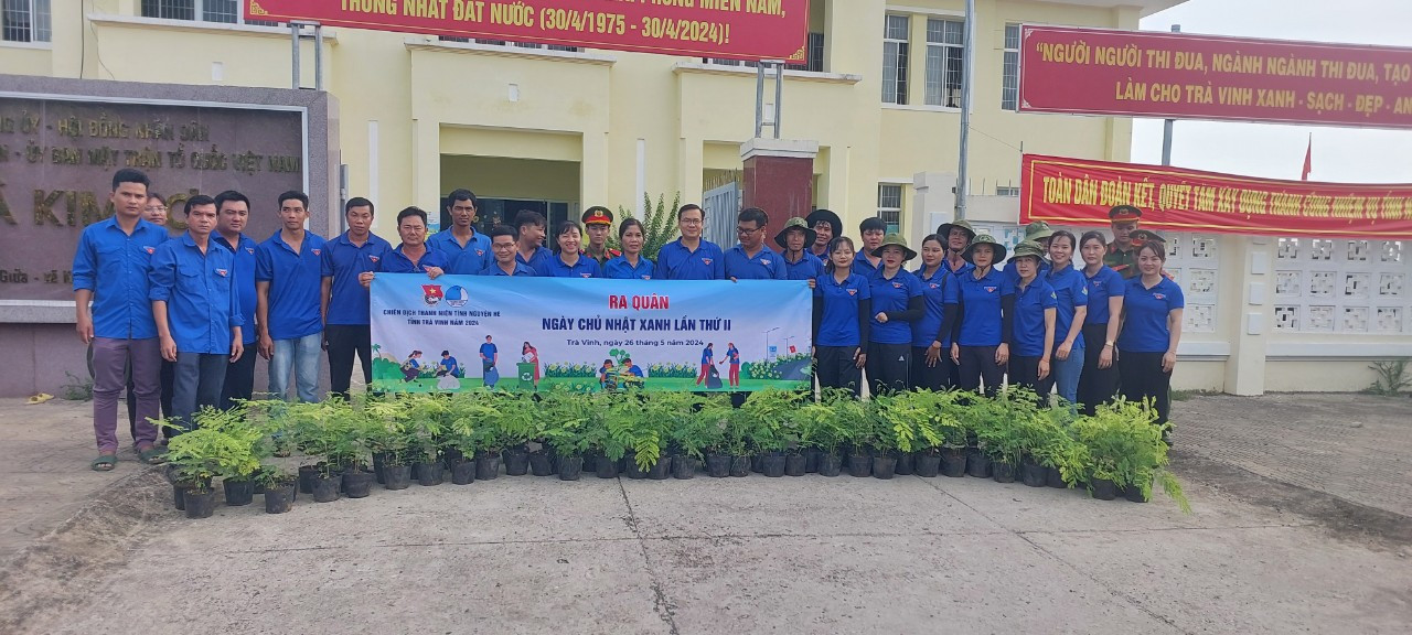 A group of people standing in front of a sign Description automatically generated
