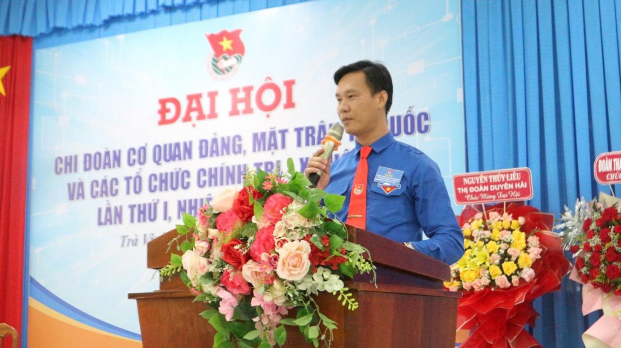 A person speaking into a microphone at a podium with flowers

Description automatically generated