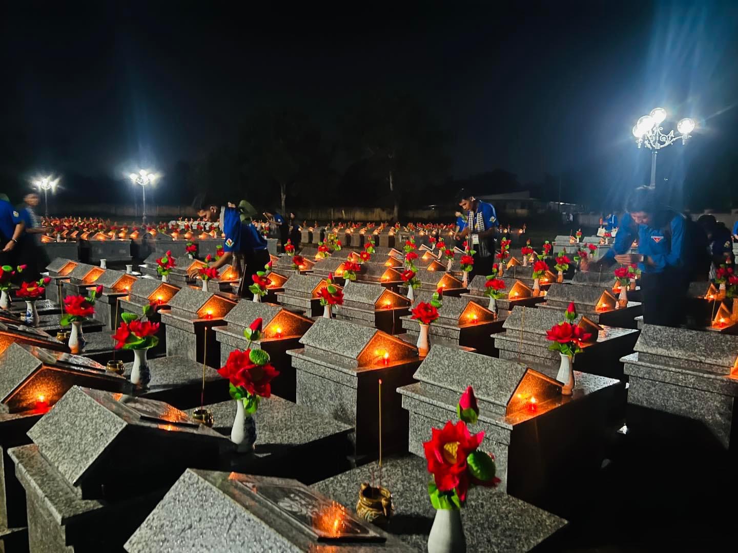 A group of people standing around a cemetery Description automatically generated