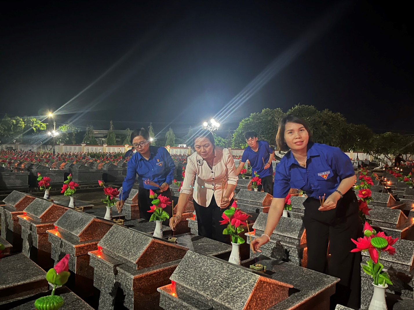 A group of people standing in a cemetery Description automatically generated
