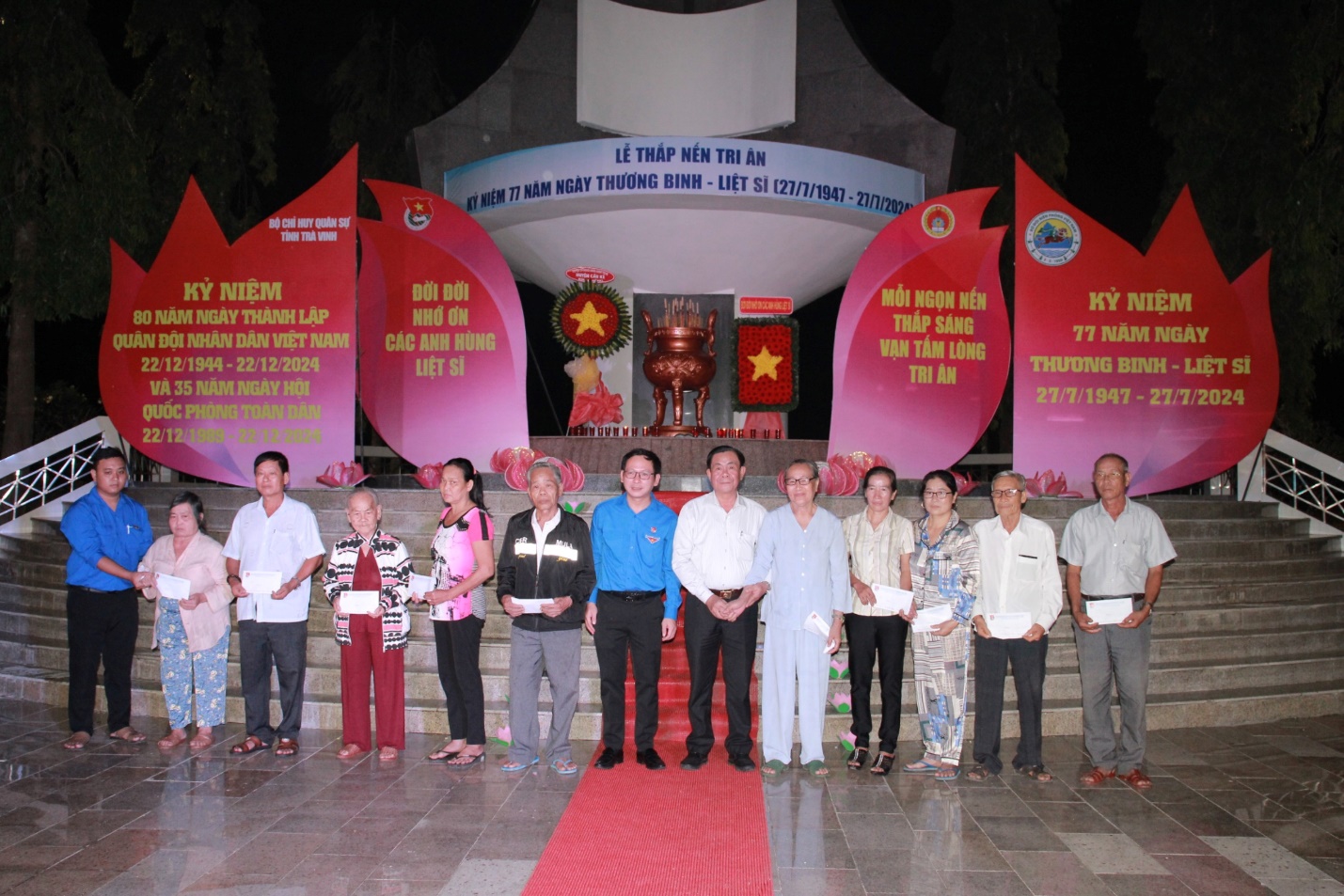 A group of people standing in front of a red carpet Description automatically generated