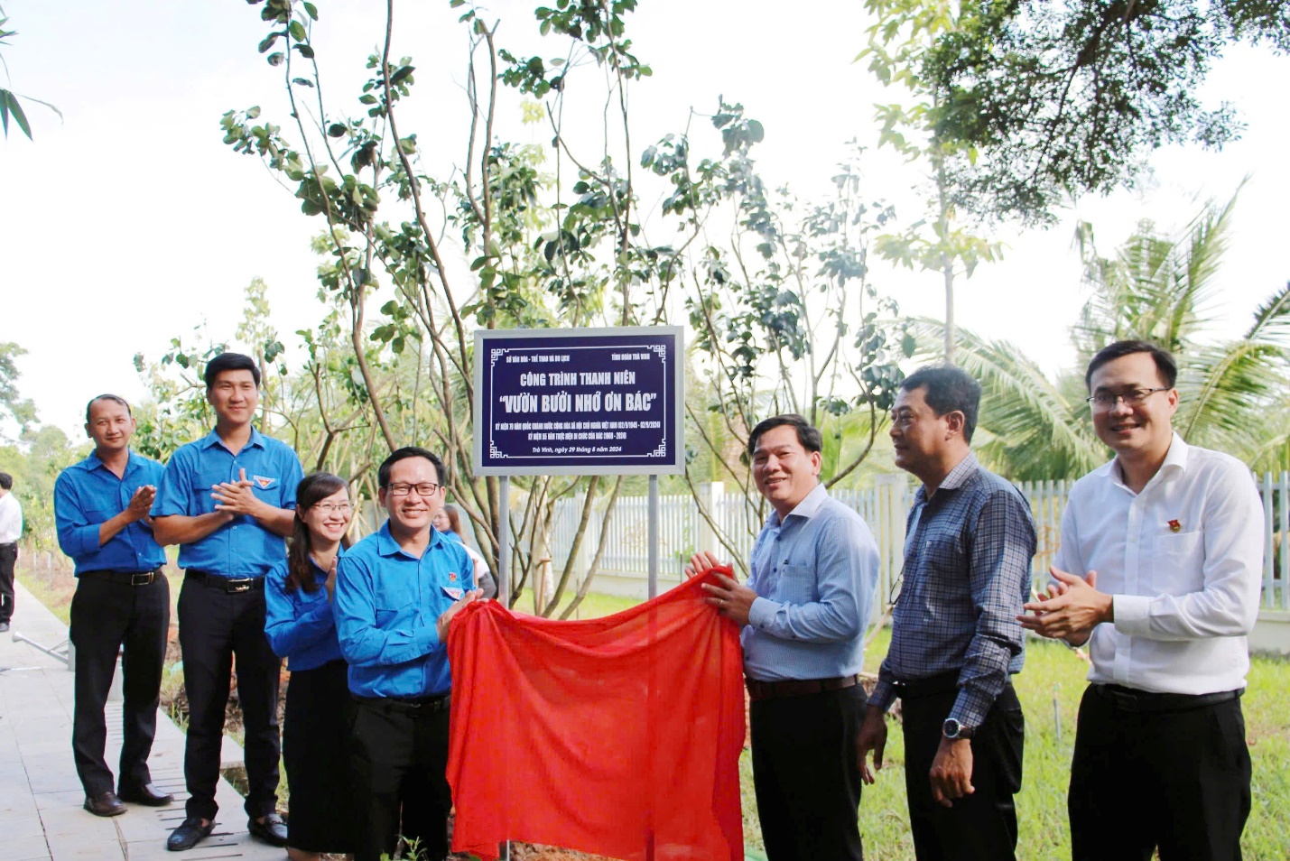A group of people standing outside holding a sign Description automatically generated