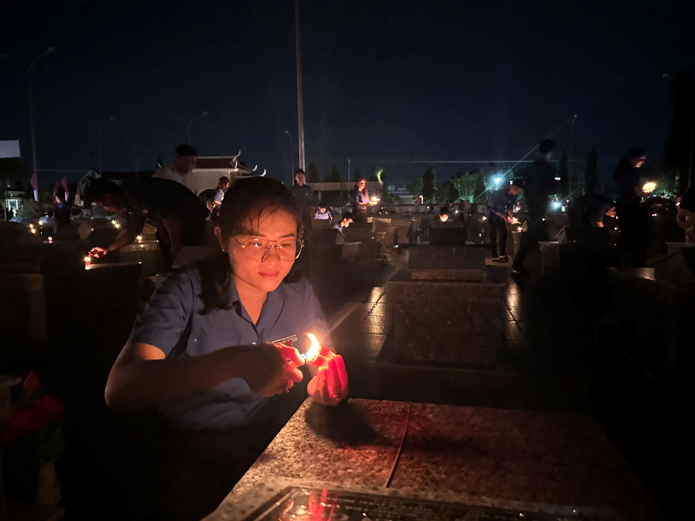 A person holding a lit candle at a table Description automatically generated