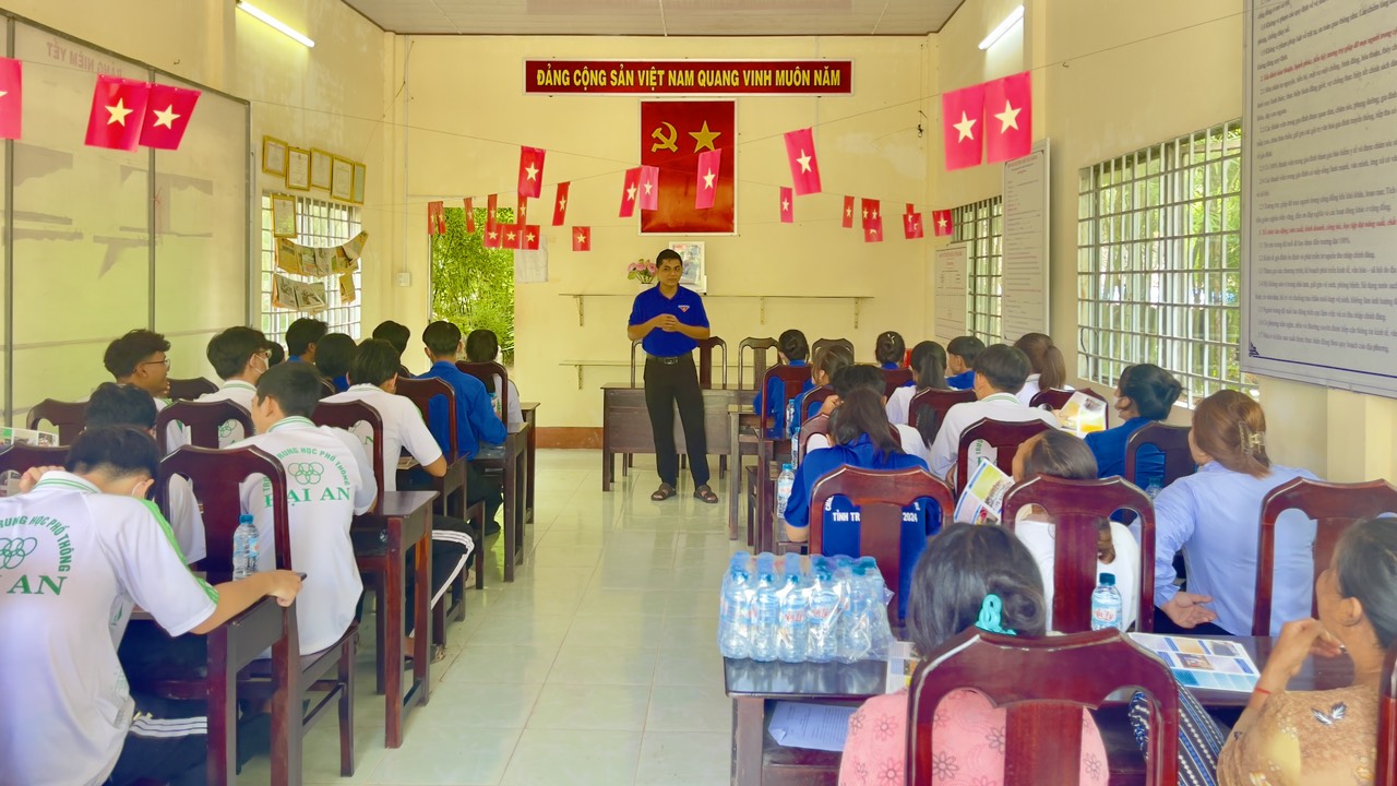 A person standing in front of a group of people in a classroom Description automatically generated