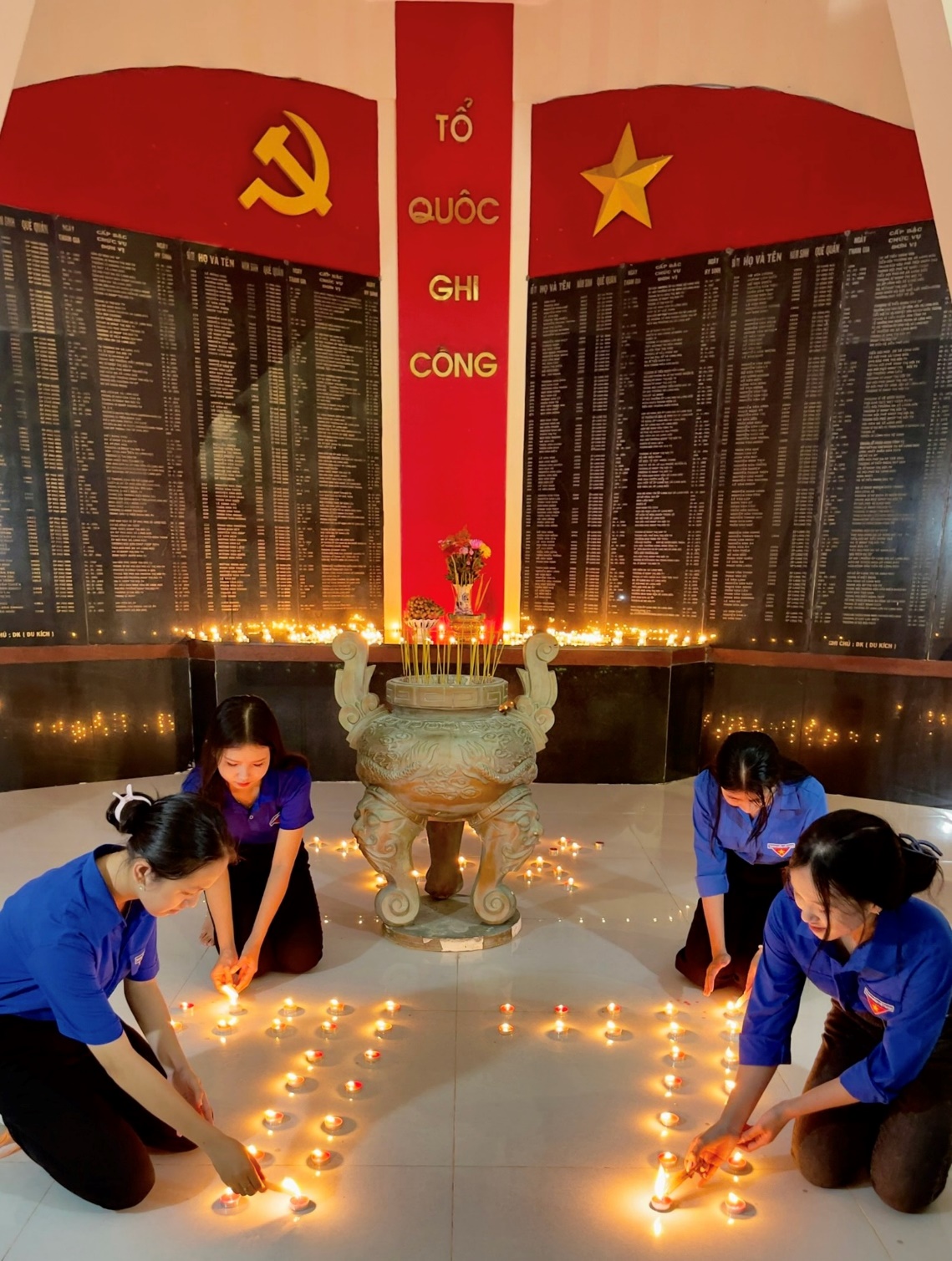 A group of women kneeling in front of a wall with candles Description automatically generated
